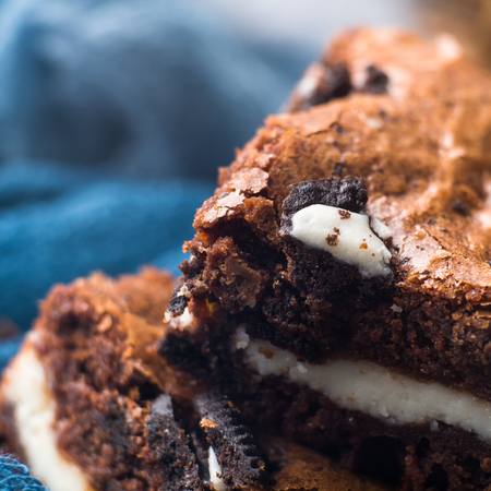 Cream cheese brownies with cookies on blue. Winter christmas treat square chocolate bars. Macro closeup detailの写真素材