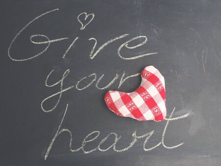 Valentine love concept card. Give your heart written with chalk on black board. Top viewの写真素材