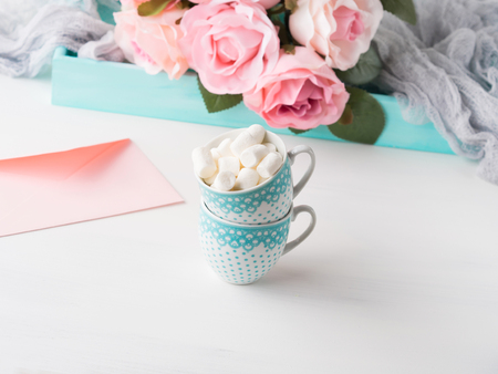 Two coffee cups with marshmallow card for Valentines or mother woman day. Wedding baby birthday romantic date invitation. Background with roses tray romantic textileの写真素材