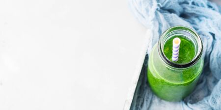 Healthy food concept green smoothie breakfast on white gray tray blue textile. Fruit vegetable juice glass bottle. Top viewの写真素材