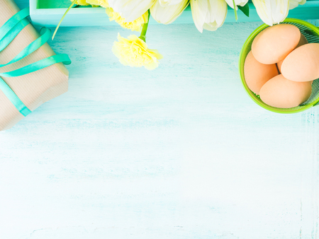 Pastel color Easter background with eggs gift yellow flowers. Top view, copy spaceの写真素材