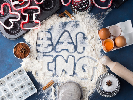 Flour letters spelling Baking with tools and sweet food ingredients sugar, eggs, cocoa, cinnamon. Top view flat lay conceptの写真素材