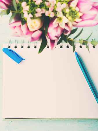 Blank empty notebook page with blue pen. Spring summer flat lay with flowers. Morning wedding planningの写真素材