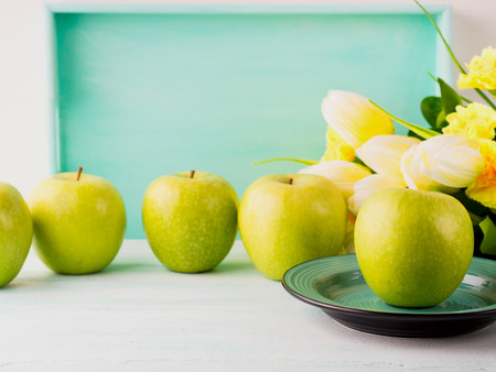White green pastel background with apples yellow flowers. Healthy food concept backdrop for writing textの写真素材