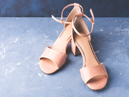 Pair of woman patent leather nude pink sandals on blue concrete textured backgroundの写真素材