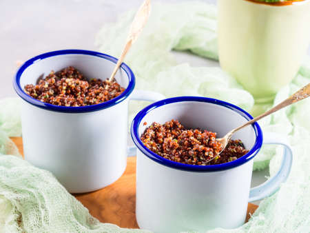 Red quinoa with vegetables in enamel mugs. Vegetarian gluten free lunchの写真素材