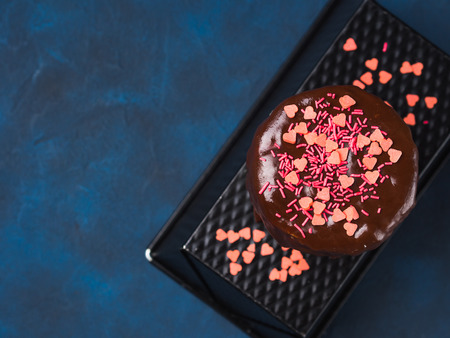 Cream cheese sponge cake with chocolate glaze and pink heart sprinkles on dark blue background. Birthday party Valentine mother day treatの写真素材