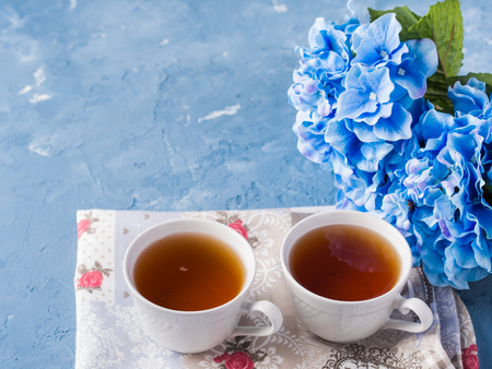 Cup of tea on blue background with flowers and textileの写真素材