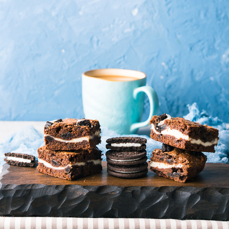 Cream cheese chocolate layer brownies with cookies on wooden serving boardの写真素材