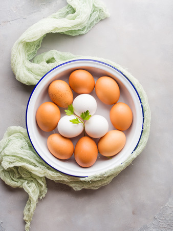 White and brown hen eggs in bowl on concrete gray backgroundの写真素材