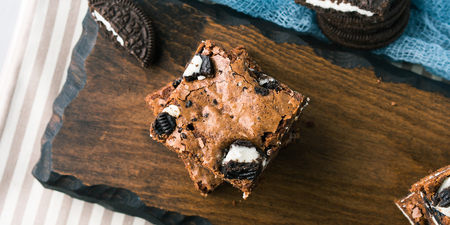 Cream cheese chocolate layer brownies with cookies on wooden serving board