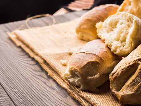 Freshly baked bread loaves on burlap dark wooden background. Texture closeup italian bakery products