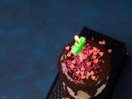 Cream cheese sponge cake with chocolate glaze and pink heart sprinkles on dark blue background. Birthday party Valentine mother day treatの写真素材