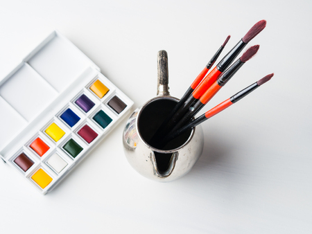 Watercolor godets and brushes on white background. Flat lay. Copy spaceの写真素材