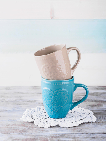 Two ceramic cups with hearts on wooden background. Vintage pastel colorsの写真素材