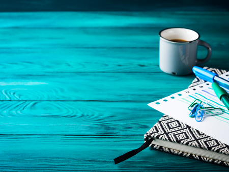 Cup of coffee, notebook and pens on dark green wooden background. Winter mood backdropの写真素材