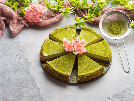 Matcha baked cheese cake and pink flowers on gray concrete backgroundの写真素材