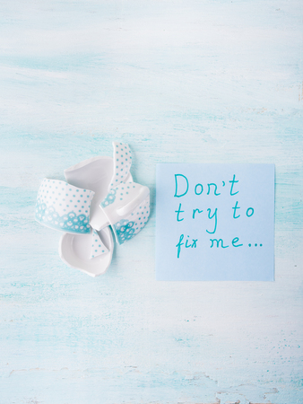 Broken cup relationship concept top view over pastel background. Flat lay