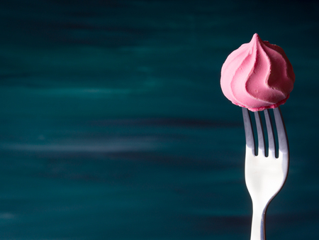 Pink meringue on fork on dark green backgroundの写真素材