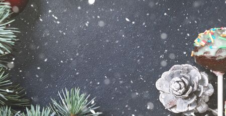 Blue spruce branches with christmas baubles on dark black concrete effect background. Snow fall flakesの写真素材