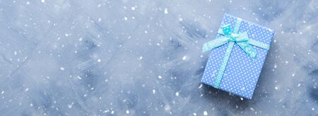 Gift box flat lay with snow flakes on blue background. Holiday surprise concept. Long bannerの写真素材
