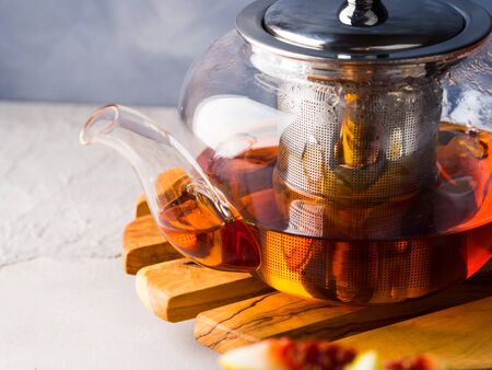 Cup of red tea rooibos and honey with glass teapot on blueの写真素材