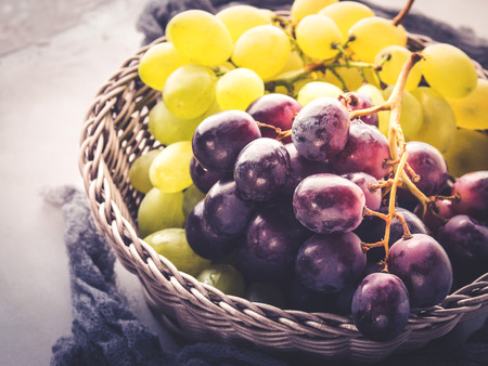 White and dark grapes in a basket on gray. Abstract minimal fruit still lifeの写真素材
