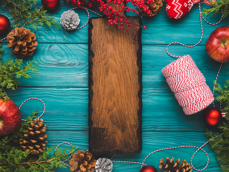 Christmas green background with wooden serving board. Festive flat lay with ornaments and pine conesの写真素材