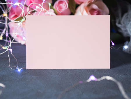 Valentine's day greeting card invitation blank paper note with colorful lights on dark background with rosesの写真素材