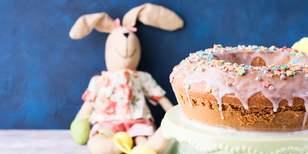 Easter bundt ring cake with sugar frosting sprinkles decorations eggs and doll bunny on dark blue background. Festive holiday home made treatの写真素材