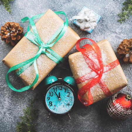 Christmas new year wrapped gifts with ribbons and snow flakes. Almost midnight on the clock