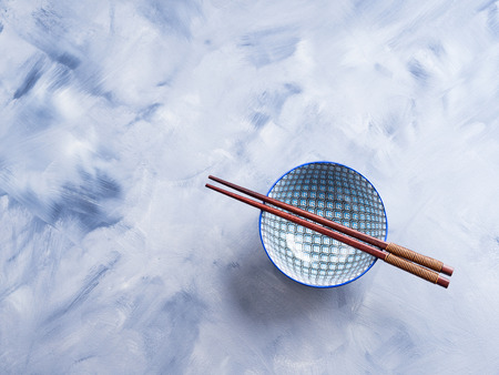 Japanese rice bowl and chopsticks on blue backgroundの写真素材