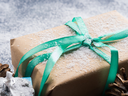 Christmas new year wrapped gift box with ribbon and snow. Pine cones and decorations. Winter festive backgroundの写真素材