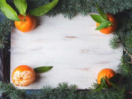 Winter tangerines frame on white rustic wooden board with spruce branchesの写真素材