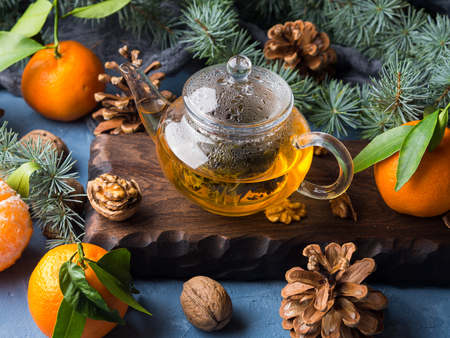 Winter tea in pot and tangerines with pine cones and fir tree branchesの写真素材