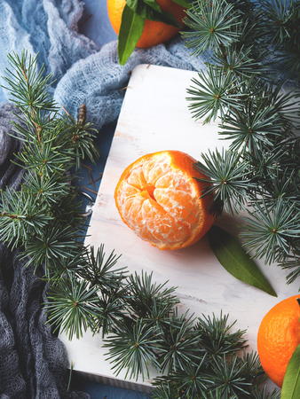 Winter tangerines frame on white rustic wooden board with spruce branches on blue backgroundの写真素材