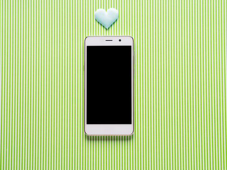Heart symbol and smartphone over green backgroundの写真素材