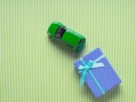 Blue gift box and a toy car on green background. Travel related present or car purchase conceptの写真素材