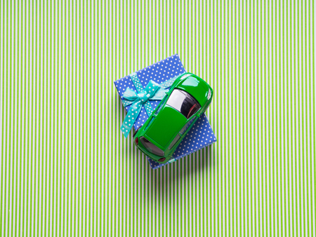 Blue gift box and a toy car on green background. Travel related present or car purchase conceptの写真素材