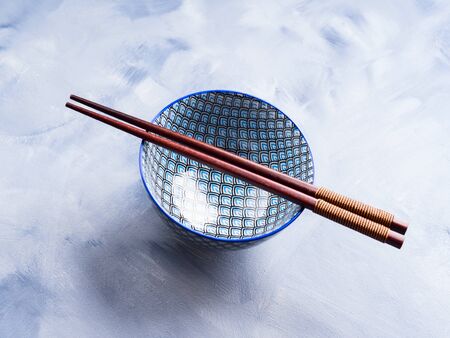 Japanese rice bowl and chopsticks on blue backgroundの写真素材