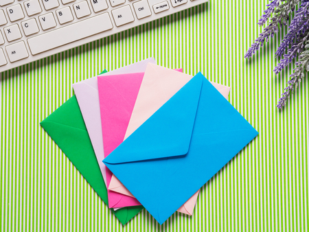 Green background with lavender flowers, keyboard, colorful envelopes. Spring easter greetings, wedding invitationsの写真素材
