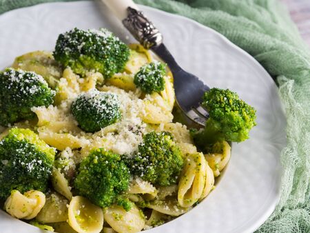 Orecchiette pasta with broccoli in white dish on wooden table. Easy recipe for lunch.の写真素材