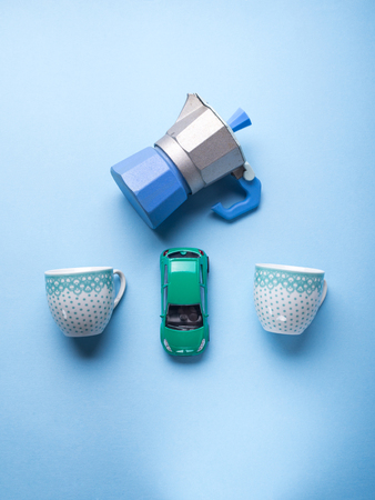 Go take coffee together concept on blue pastel background with a coffee maker, two cups and a toy car. Flat layの写真素材