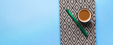 Cup of coffee, pen and a notebook on blue background. Planning, writing conceptの写真素材