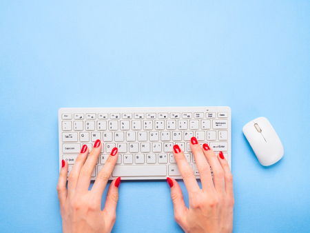 White keyboard with hands of a woman digiting. Minimal blue background. Online blog conceptの写真素材