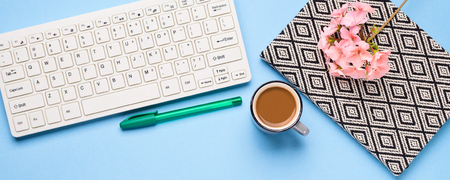 Keyboard, notebook, pen and a cup of coffee. Writing, studying and blogging concept. Pink flowers