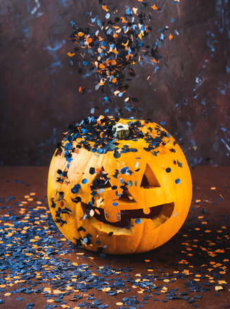 Halloween carved squash and confetti. Dark Holiday spooky background still lifeの写真素材