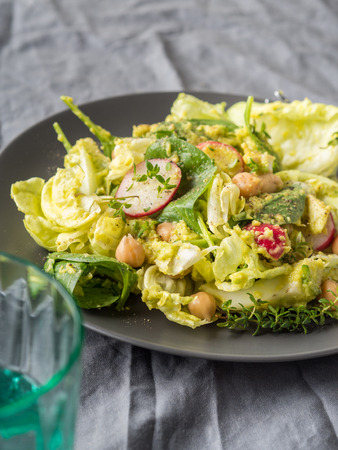 Plant based avocado spinach salad with chickpeas, lettuce and radish on gray table clothの写真素材