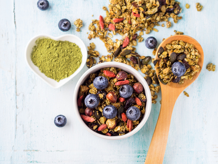 Home made matcha green tea granola in bowl on pastel turquoise background. Oats granola with goji berries, dried fruit, seeds and nuts. Healthy breakfast conceptの写真素材