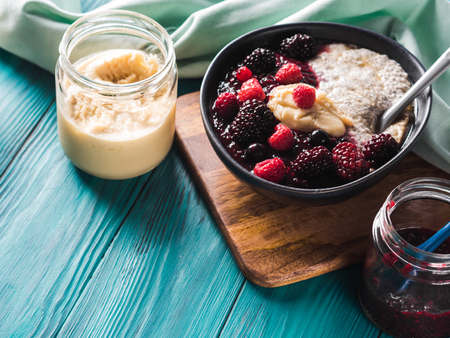 Vegan cashew milk Chia pudding with berries and home made almond butter served in a bowl on wooden boardの写真素材